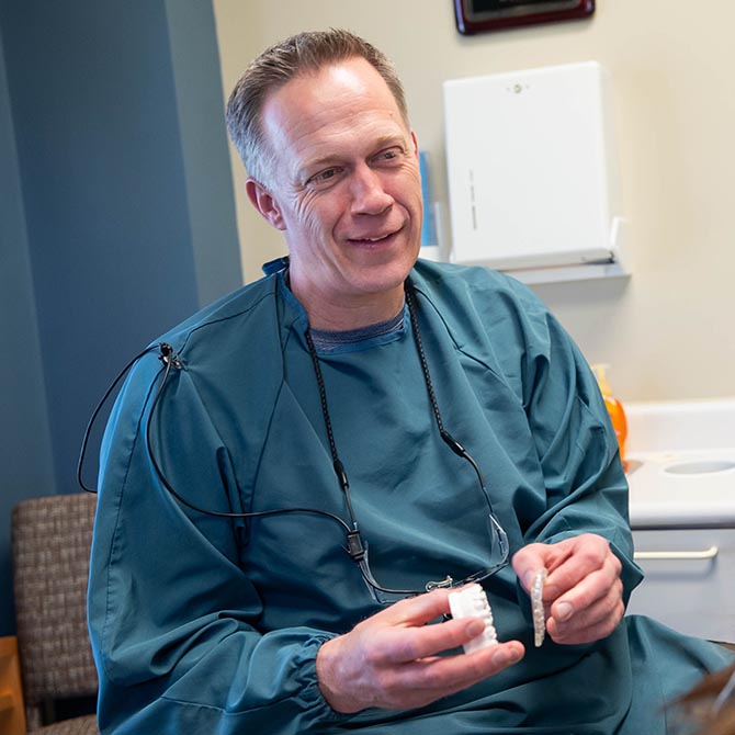 Dr. Adam Fulton holding a dental model inside the clinic of Guilford Hills Dental Care